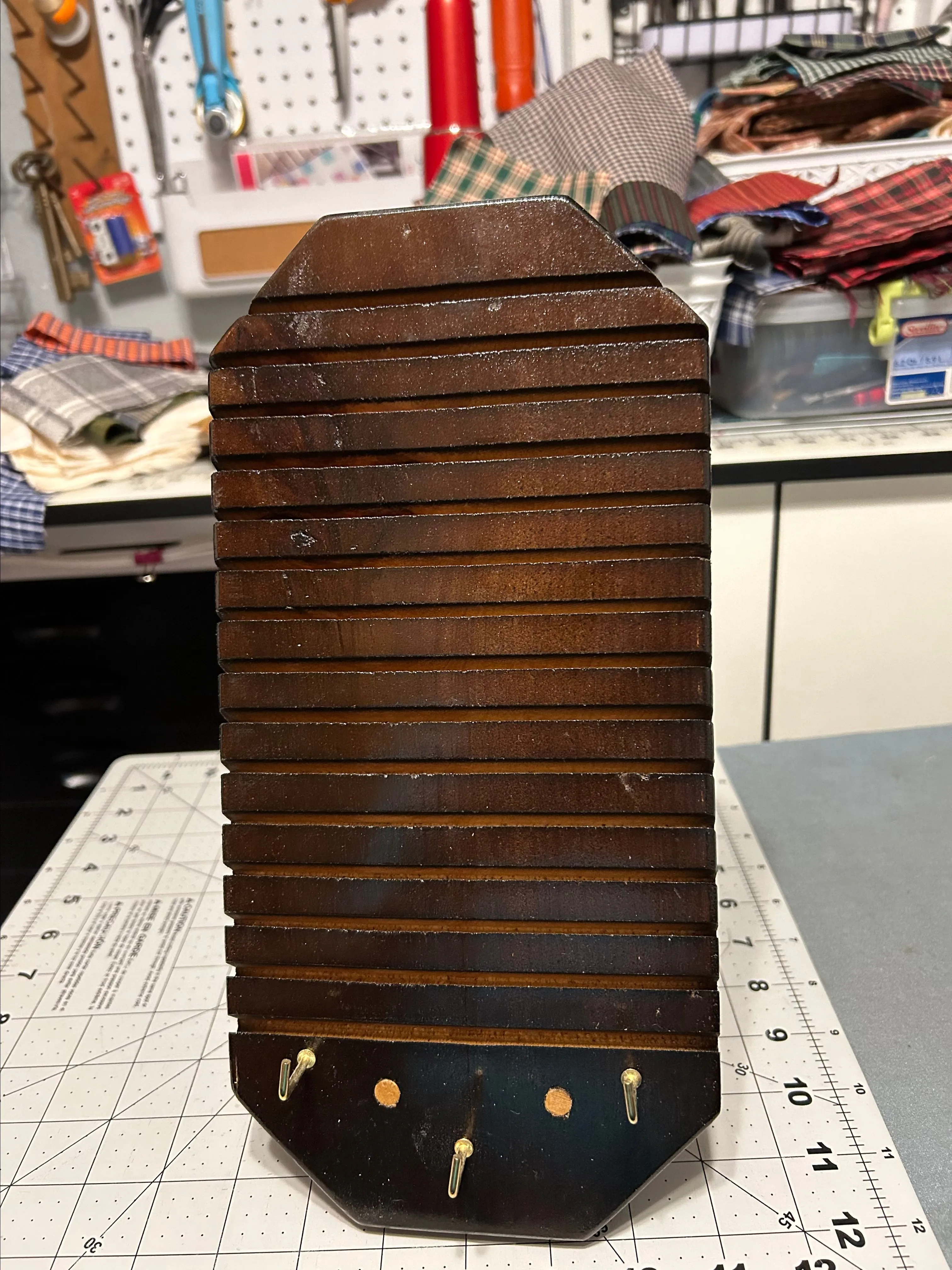 Product image for A ruler holder for quilt rulers hangs on the wall, holds them in the slots or behind the board