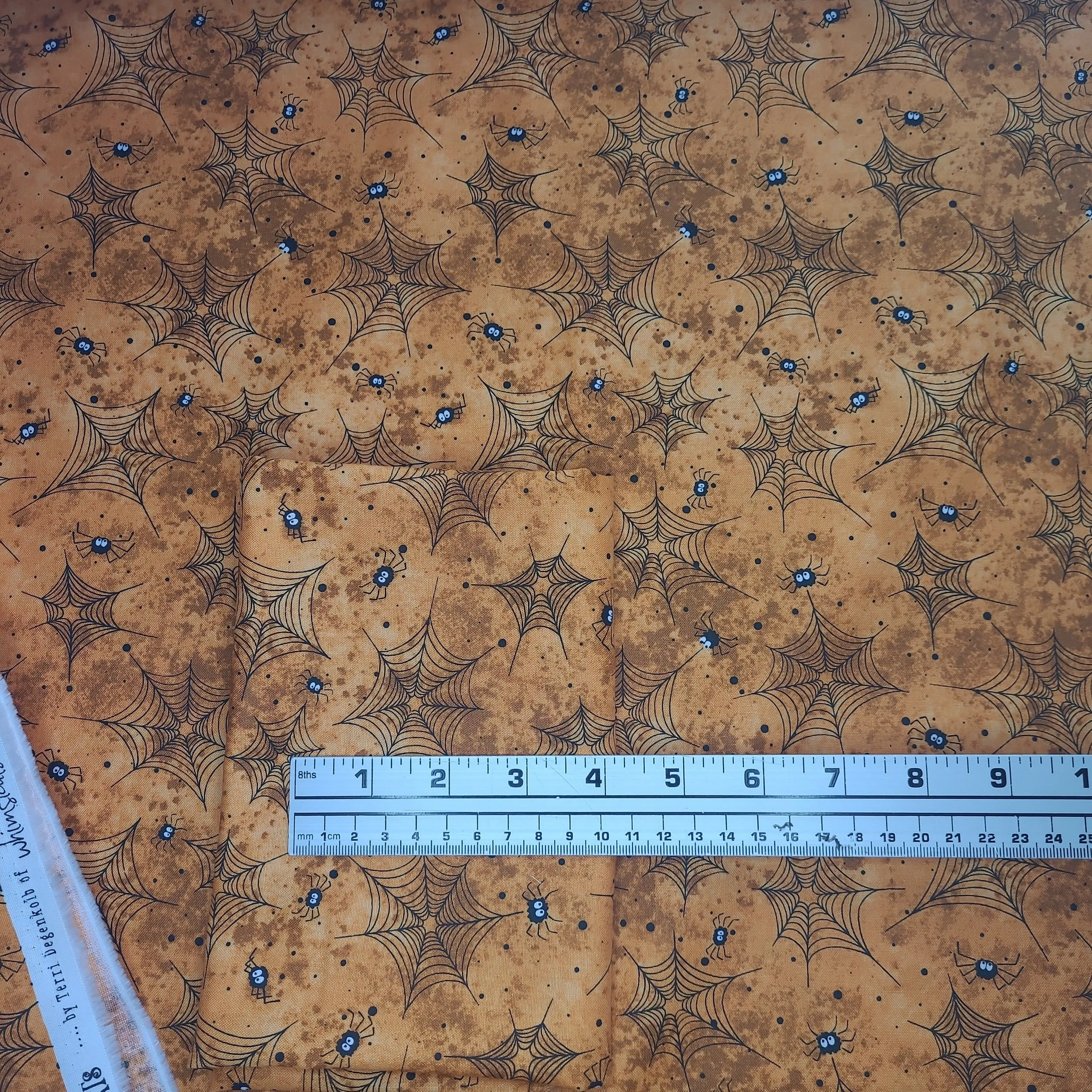 Product image for 1/2 yard- Halloween orange with black spiders and spiderwebs. Windham fabric scaredy cats